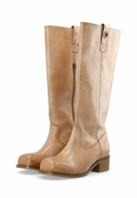 Botas altas de cuero marrón claro con una textura suave, cremallera lateral y un pequeño tacón de madera. Incluye un acento circular en el tacón.