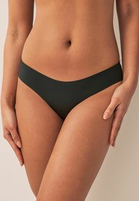 Bas de bikini noir avec une texture lisse, design taille basse, côtés étroits et bords sans couture, mettant en avant un style minimaliste.