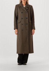 Brun uld dobbeltknappet frakke med store sorte knapper, slået krave, sidelommer og lange ærmer. Skræddersyet, lige silhuet.