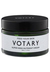 Grünes Glasgefäß mit einem schwarzen Schraubdeckel. Weiße Etikette mit schwarzem Text: "Votary Super Seed Nutrient Cream, 50ml." Glatte Textur, schlichtes Design.