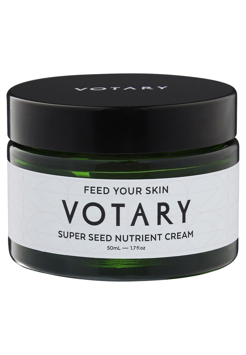 Grünes Glasgefäß mit einem schwarzen Schraubdeckel. Weiße Etikette mit schwarzem Text: "Votary Super Seed Nutrient Cream, 50ml." Glatte Textur, schlichtes Design.