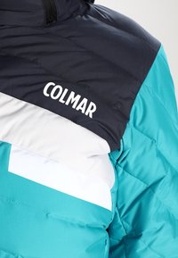 Turkusowa puchowa kurtka z ciemnogranatową górną częścią i białą wstawką. Logo "COLMAR" wyraźnie widoczne na ramieniu w białym kolorze.