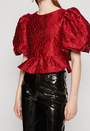 Rode blouse met bloemmotief en pofmouwen, gestructureerd van textiel, met een peplum taille, gecombineerd met glanzende zwarte nepleren broek met een subtiel slangenhuidpatroon.