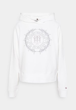 Biała bluza z kapturem Tommy Hilfiger z okrągłym haftowanym logo i wieńcem laurowym na piersi, małe logo flagi na lewym mankiecie.