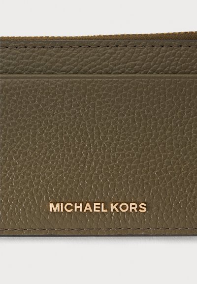 Section de portefeuille en cuir texturé vert olive avec le logo doré « MICHAEL KORS » embossé près du bord inférieur.