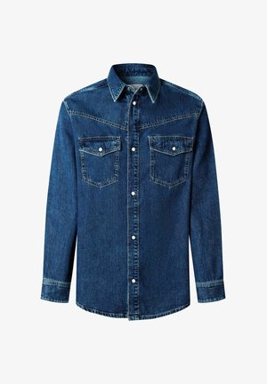 Tumši zils džinsa krekls ar garām piedurknēm, ar pogām aiztaisāms priekšā, divām krūšu kabatām un kontrastējošām šuvju detaļām. Ir klasisks apkaklis.