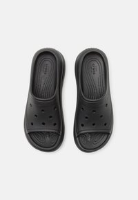 Sorte svarte slip-on sandaler med teksturert overdel og perforerte hull for pusteevne. Komfortabelt fotseng med sportslige designelementer.