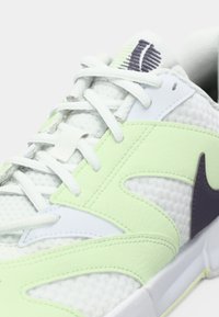 Võrkkangaga valge ja helerohelise ülapinnaga vabaajajalats, millel on tekstuuriga disain, valged paelad ja tumelilla aktsent.