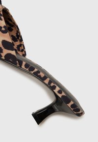 Open-toe high heel sandal featuring a beige and black leopard print fabric, a sleek black heel, and a smooth curved design.