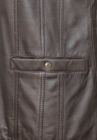 Nahaufnahme einer braunen Lederjacke mit Druckknopf und horizontalem Taschendetail. Die Textur ist glatt mit sichtbaren Nähten.