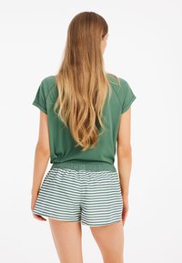 Top de manga corta verde combinado con pantalones cortos a rayas en verde y blanco. Los pantalones cortos tienen una cintura elástica y un corte holgado.