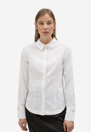 Camisa blanca de botones con cuello clásico, ajuste entallado y acentos de botones dorados en los puños. Presenta un sutil detalle bordado.