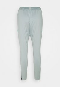 Helle graue Sporthosen mit schmalem Schnitt, elastischem Bund und seitlichen Schlitzen am Knöchel. Glatte Textur und atmungsaktiver Stoff.