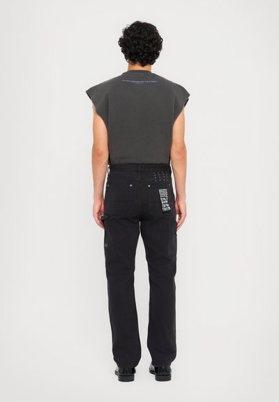 Black cargo pants with various pockets, paired with a dark gray sleeveless shirt featuring text on the back. Casual design and clean lines.