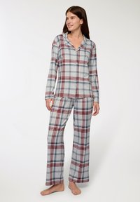 Completo pigiama a quadretti in grigio chiaro con motivi rossi e blu navy. Presenta una camicia con bottoni a maniche lunghe e pantaloni coordinati.
