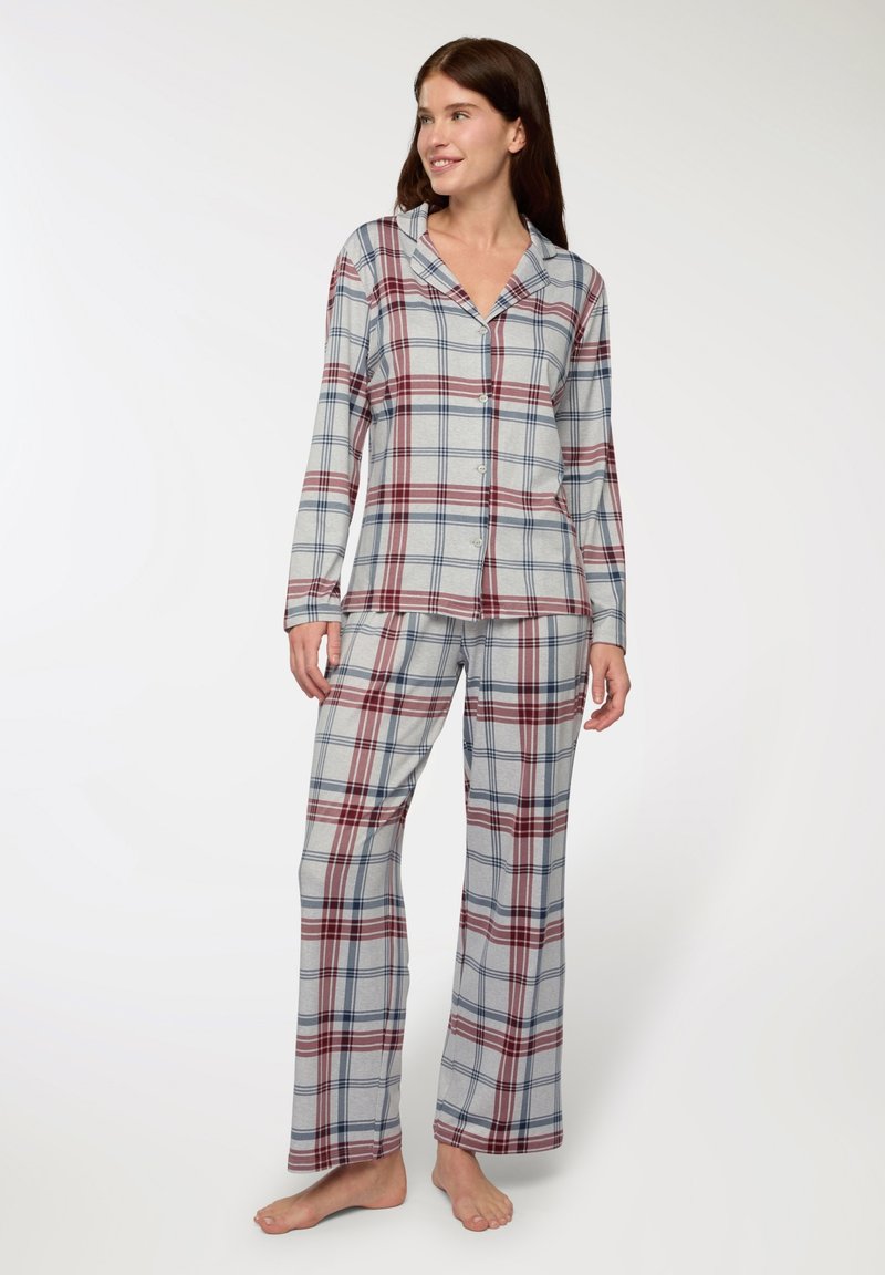 Completo pigiama a quadretti in grigio chiaro con motivi rossi e blu navy. Presenta una camicia con bottoni a maniche lunghe e pantaloni coordinati.