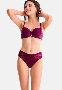 Soutien-gorge en dentelle bourgogne avec armatures et bretelles réglables, associé à un slip assorti avec des accents en dentelle géométrique et une taille lisse.