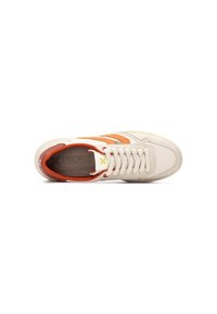 Zapatilla blanca con acentos en naranja y beige. Presenta una parte superior de cuero suave, puntera redonda, cierre de cordones y suela de goma texturizada.