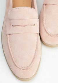 Różowe zamszowe loafersy z przyszytym przodem, niewielkim obcasem oraz klasycznym designem z zaokrąglonym noskiem i subtelnymi detalami.