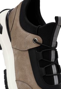 Tige en brun clair texturé avec des accents noirs, dotée d'un col en maille noir et de lacets, complétée par une semelle blanche et des détails gris.