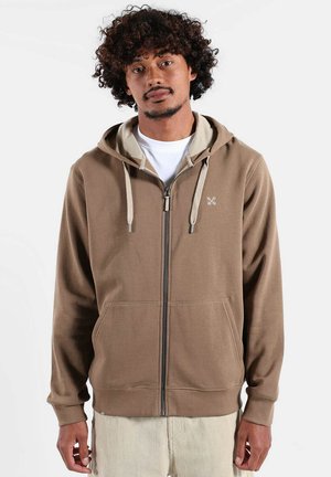 Sweat à capuche marron avec fermeture éclair, doublure de capuche plus claire, poches frontales et cordons de serrage. Présente un logo sur la poitrine gauche, des poignets et un ourlet côtelés.