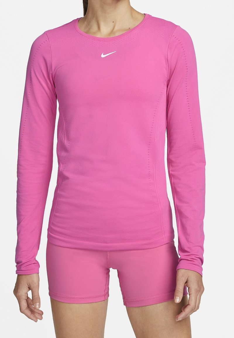Maglietta sportiva a maniche lunghe e pantaloni short coordinati di un vivace colore rosa. Realizzata in materiale liscio e elastico, con scollatura a girocollo e dettagli di ventilazione sottili.