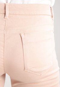  Lichtroze denim jeans met een slim fit, voorzien van achterzakken en subtiele stikdetails. Gladde textuur en klassieke ontwerpelementen.