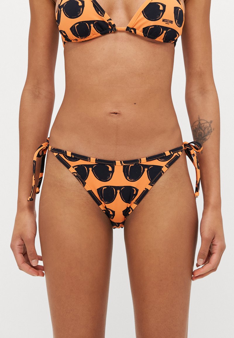 Orange bikini with black sunglasses pattern. Two-piece design featuring adjustable ties on the sides of the bottoms. Textured fabric.