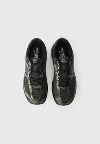 Svarta Nike-sneakers med mesh-överdel, vadderad tunga, snörning, texturerad sula och reflexdetaljer. Ovanifrån visar en symmetrisk design.