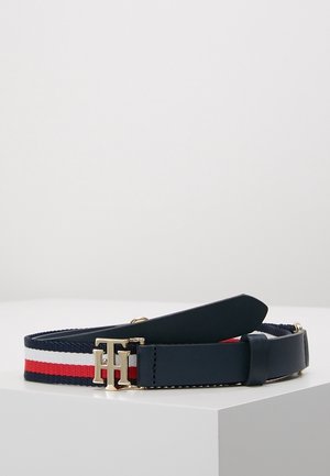 Marineblauwe, witte en rode gestreepte stoffen riem met gouden "TH" logo gesp en marineblauwe leren riem op een witte ondergrond.