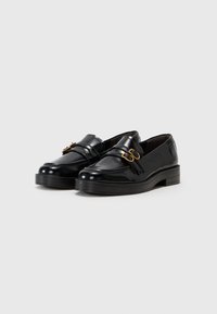 Svart patentlær loafers med runde tær, med gullfargede metall detaljer og tykk svart kile såle. Glatt tekstur med minimale detaljer.