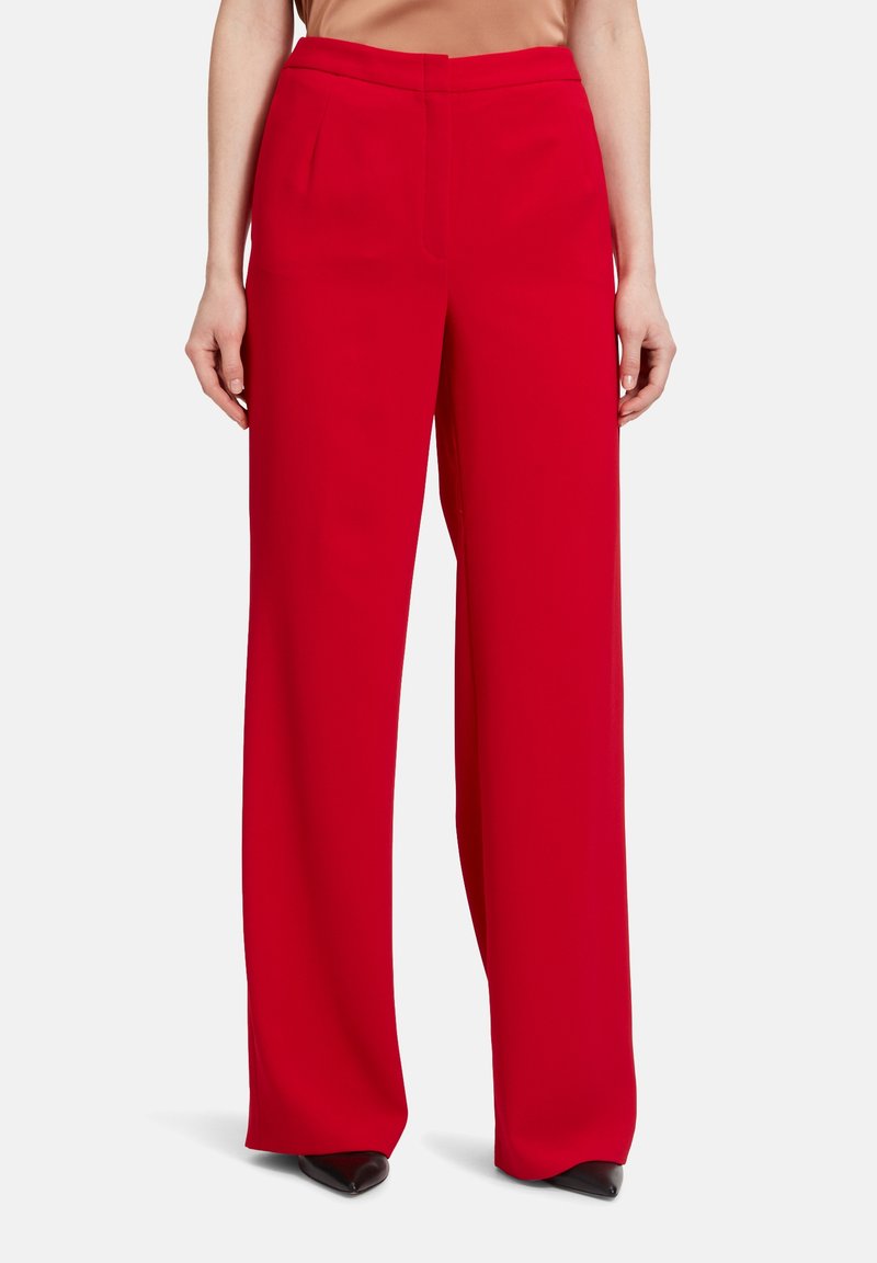 Pantalons larges rouges avec une texture lisse, dotés de poches avant et d'une taille ajustée. Le tissu est léger et tombe élégamment.