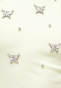 Λευκό υφασμάτινο ύφασμα με ριγέ υφή, διάσπαρτα ασημένια κρυσταλλοειδή διακοσμητικά πεταλούδες και μικρούς στρογγυλούς κρυστάλλους.