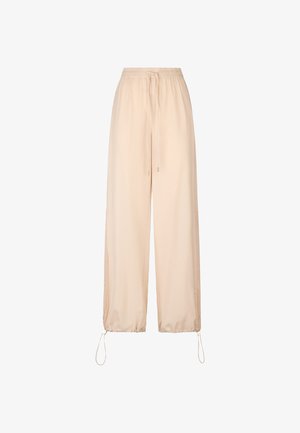 Pantaloni jogger beige chiaro realizzati in un tessuto morbido e leggero. Presentano una vita elastica, un cordoncino e pannelli laterali in rete.