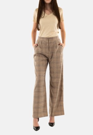 T-shirt beige à col en V associé à un pantalon à carreaux taille haute dans des tons de marron, doté de poches latérales et d'une coupe décontractée. Chaussures à talons.