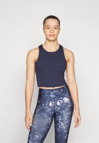 Tamno plavi crop top s okruglim izrezom i minimalnim šavovima, uparen s tajicama koje se pristaju i imaju teksturirani mramorni uzorak.