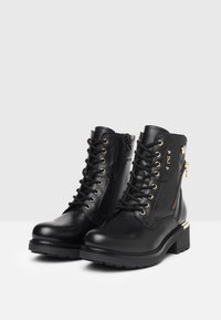 Black leather ankle boots with lace-up front, gold eyelets, and side zipper, featuring a chunky heel and textured sole.