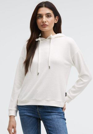 Weißer Pullover-Hoodie aus weichem Stoff, mit langen Ärmeln, einer Kordelzugkapuze und einem leicht lockeren Schnitt. Kombiniert mit Jeans.