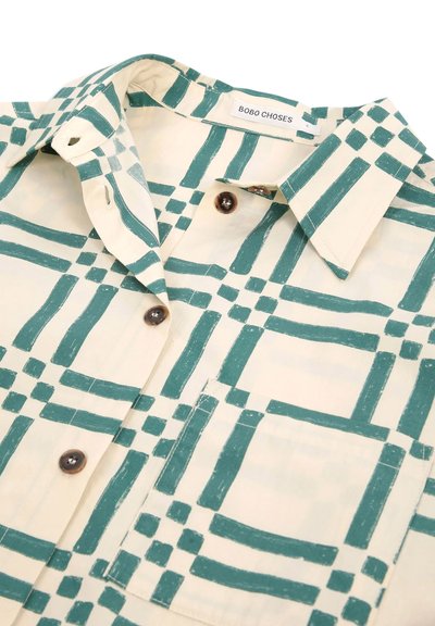 Chemise à col avec motif à carreaux vert olive sur tissu crème, boutons marron et poche poitrine, étiquetée Bobo Choses.