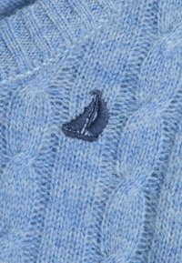 Maglione azzurro chiaro a lavorazione a maglia con un motivo texturizzato e un logo di una barca a vela ricamato blu scuro sul davanti. Materiale in morbida lana.