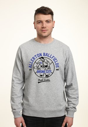 Felpa grigia con colletto a girocollo; presenta una grafica stampata di un giocatore di baseball, testo "Allerton Ballfields Bronx City 1961" in blu e nero.