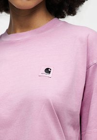 Ροζ βαμβακερή μπλούζα με στρογγυλή λαιμόκοψη και κοντά μανίκια. Διαθέτει τετράγωνο μαύρο λογότυπο στο αριστερό στήθος. Λείο ύφασμα, άνετη εφαρμογή.