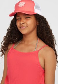 Helles pinkes ärmelloses Oberteil aus strukturiertem Material, kombiniert mit einer korallenfarbenen und weißen Mesh-Cap mit einem weißen Herz-Logo.