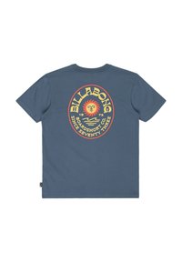 Modrá tričko s krátkym rukávom s okrúhlym žltým a červeným slnečným logom a textom "Billabong Boardshort Co. Od roku sedemdesiat tri" na chrbte.