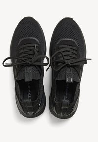 Baskets en tricot noir avec un dessus texturé, bout arrondi, lacets plats et tirettes. Semelles en caoutchouc épaisses pour un amorti et une adhérence.
