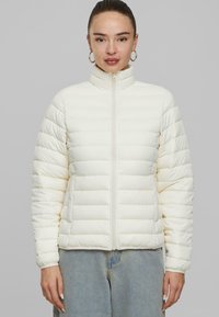 Doudoune blanche avec col haut, fermeture éclair à l'avant et poignets élastiques. Présente un design matelassé horizontal et une texture douce et lisse.