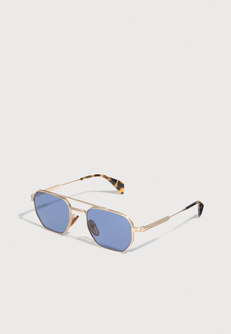 Γυαλιά ηλίου με χρυστό μεταλλικό σκελετό, φακούς με μπλε απόχρωση και άκρα κεραιών με μοτίβο χελώνας, πάνω σε λευκή επιφάνεια.
