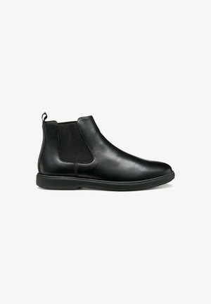 Bottines Chelsea en cuir noir avec des panneaux latéraux élastiques, texture lisse, bout rond et une languette pour un enfilage facile. Semelle plate en caoutchouc noir.