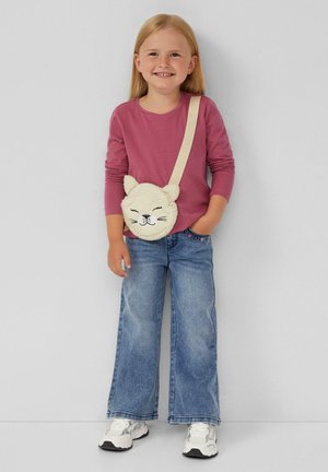 Ronde, crème-kleurige pluizige tas met een kattengezicht en oren, gedragen met een lichtbeige schouderband; gecombineerd met een roze longsleeve shirt en een blauwe broek.