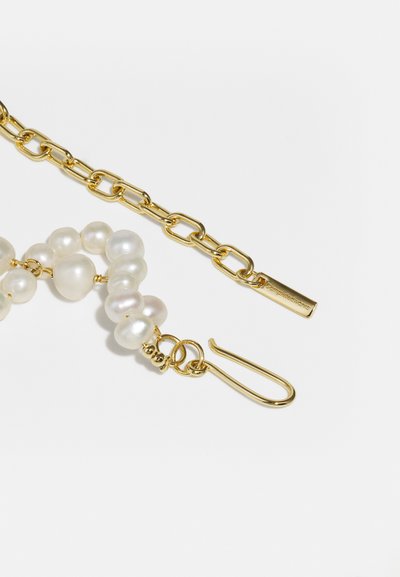 Χρυσή αλυσίδα με φυσικές πέρλες. Οι πέρλες έχουν ακανόνιστο σχήμα και κρεμ λευκή απόχρωση. Διαθέτει κούμπωμα με γάντζο και μια μικρή εγχαραγμένη ετικέτα.